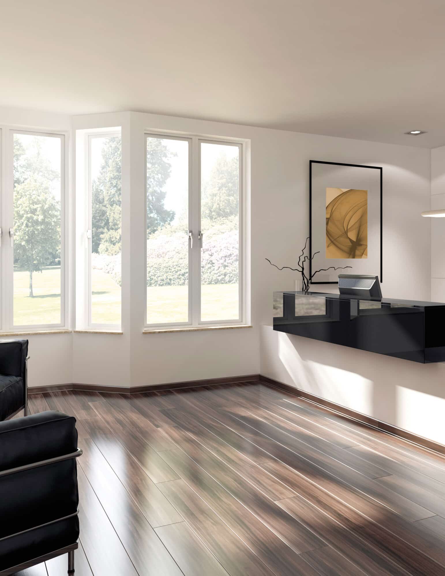 Heller, moderner Raum mit großen Fenstern, die viel Tageslicht hereinlassen. Der Boden ist aus glänzendem Holz, und in der Ecke steht ein schwarzes Sofa. An der Wand hängt ein minimalistisches Kunstwerk. Ein schwarzer Empfangstresen ist im Hintergrund sichtbar.