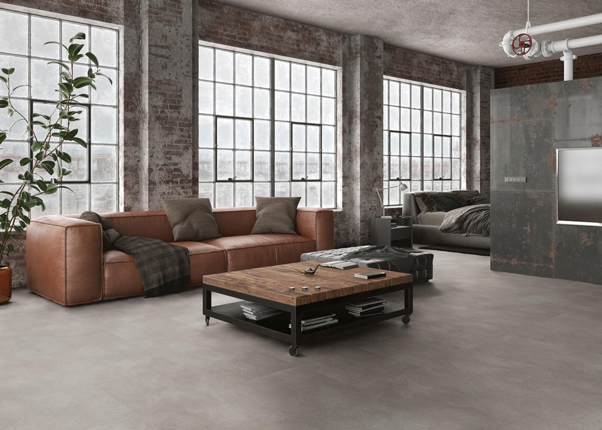 Ein modernes Wohnzimmer mit großen Fenstern, einer rustikalen Ziegelwand und einem gemütlichen Ledersofa. In der Mitte steht ein quadratischer Holztisch mit schwarzen Metallbeinen, darauf liegen einige Bücher und Gegenstände. Im Hintergrund ist ein Bett mit grauer Bettwäsche und eine stilvolle Lampe zu sehen.